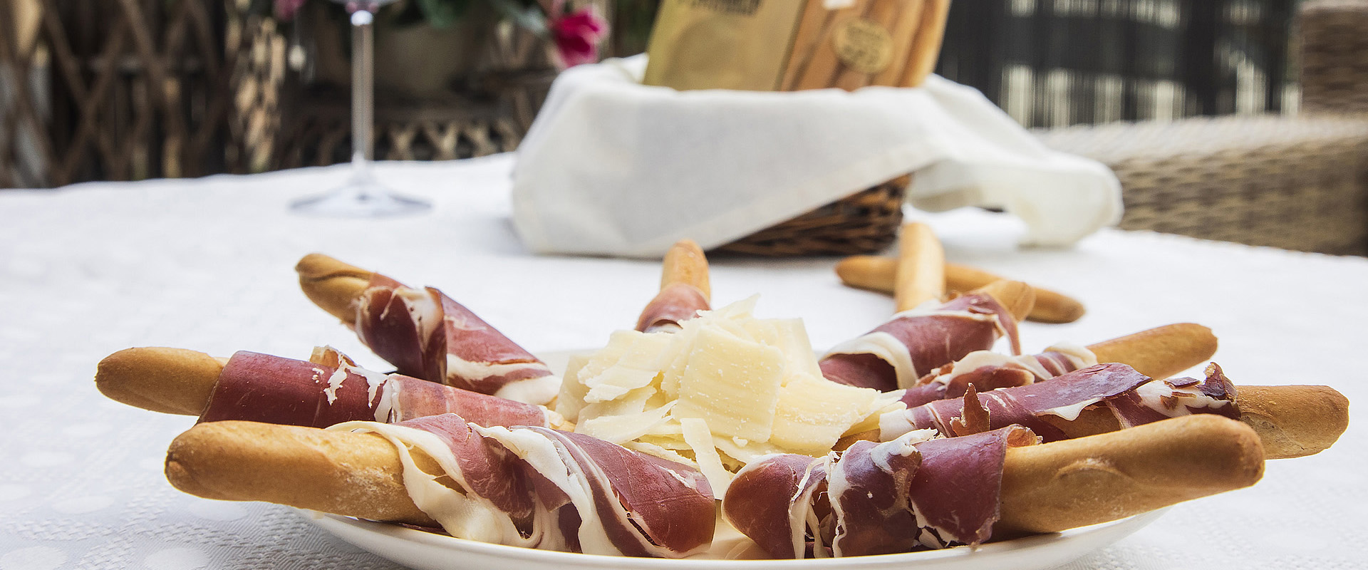 Foto de un plato de jamón y queso, con el jamón enrollando unos palitos de pan de Rosquillas Ñora